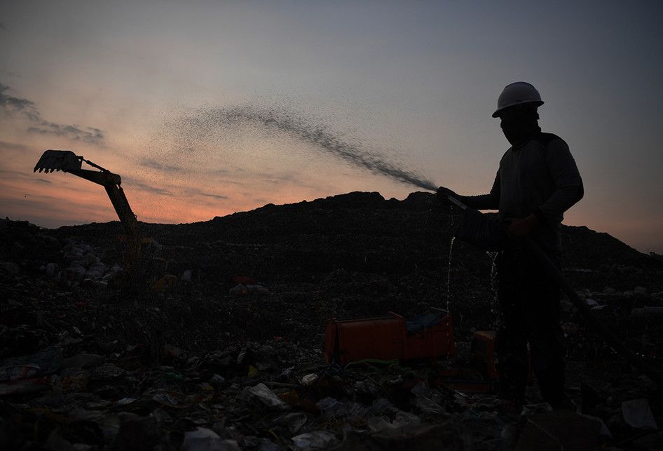 Pekerja menyemprotkan IM6 pada tumpukan sampah di Tempat Pembuangan Akhir (TPA) Benowo, Surabaya, Jawa Timur