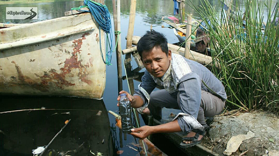 salah satu warga mencoba melihat hitamnya air sungai melalui botol plastik