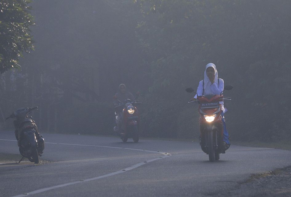 Kondisi ruas Jalan Banda Aceh - Meulaboh di kawasan Kecamatan Samatiga, Aceh Barat, yang diselimuti kabut asap akibat kebaran lahan dan hutan gambut, Selasa (30/07/2019). Sebanyak lima siswa MTsN 1 Aceh Barat mengalami pingsan dan sesak napas akibat kabut asap kebakaran hutan dan lahan gambut.