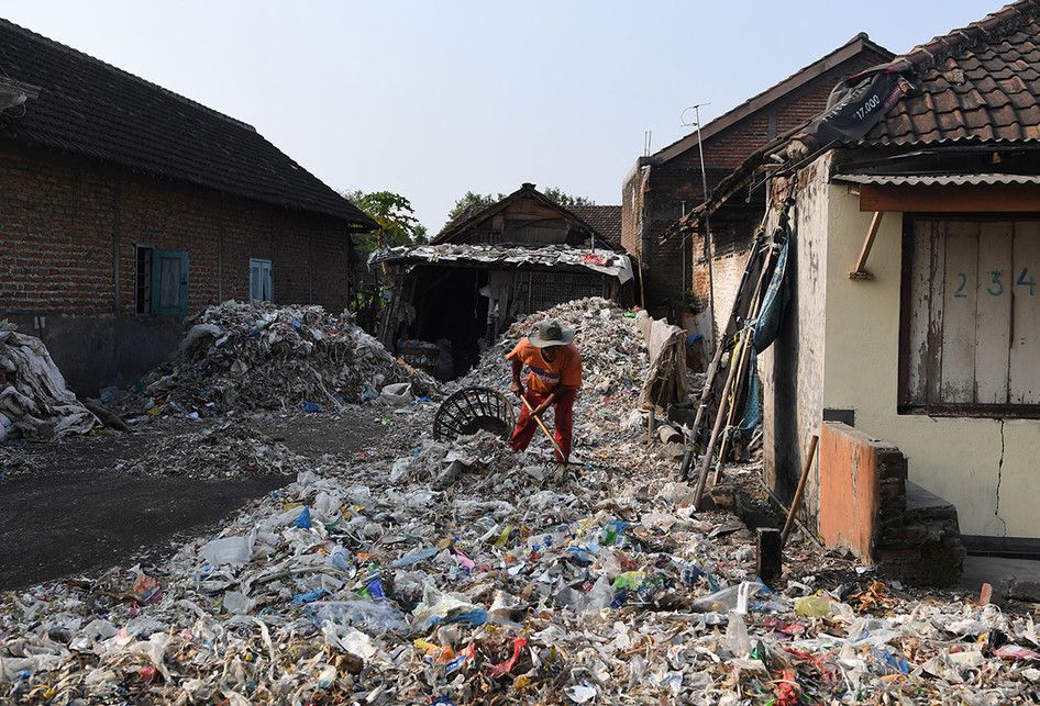 Foto dirilis Selasa (6/8/2019), menunjukkan seorang warga memilah tumpukan sampah plastik impor sekitar rumahnya di Desa Bangun di Mojokerto, Jawa Timur. Indonesia diperkirakan setiap harinya menerima sedikitnya 300 kontainer sampah yang sebagian besar menuju ke Jawa Timur, diduga dampak kebijakan China yang menghentikan impor sampah plastik dari sejumlah negara di Uni Eropa dan Amerika.