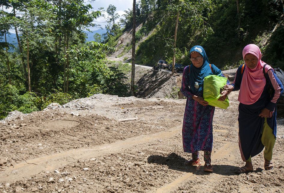 Warga terpaksa berjalan kaki melintasi jalan poros Palu-Kulawi yang longsor di Desa Namo, Kecamatan Kulawi, Kabupaten Sigi, Sulawesi Tengah, Rabu (14/8/2019).  Jalan yang longsor pada Selasa (13/8/2019) malam akibat curah hujan yang tinggi itu memutuskan satu-satunya akses keluar masuk di wilayah it
