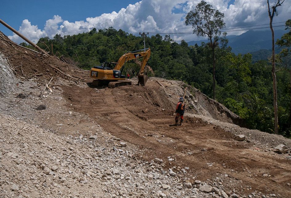 Pekerja menyingkirkan material longsoran yang memenuhi badan jalan poros Palu-Kulawi yang longsor di Desa Namo, Kecamatan Kulawi, Kabupaten Sigi, Sulawesi Tengah, Rabu (14/8/2019).  Jalan yang longsor pada Selasa (13/8/2019) malam akibat curah hujan yang tinggi itu memutuskan satu-satunya akses kelu