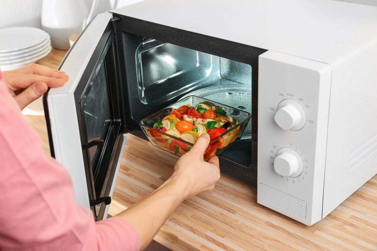Woman putting bowl with vegetables in microwave oven, closeup; Shutterstock ID 1011440542; Job (TFH, TOH, RD, BNB, CWM, CM): TOH