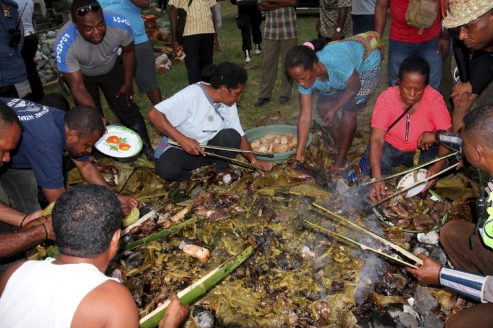 Sejumlah ibu di Ransiki, ibu kota Kabupaten Manokwari Selatan, Provinsi Papua Barat, mengambil daging ayam yang siap untuk dimakan yang dimasak dengan proses pembakaran batu, Sabtu (31/10). Memasak makanan dengan bakar batu adalah tradisi yang berkembang pada masyarakat Papua. (Foto bawah) sejumlah 