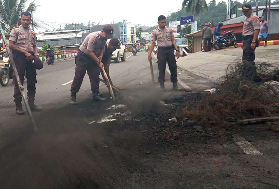 Sejumlah polisi membersihkan sisa kerusuhan di salah satu ruas jalan di Manokwari, Papua Barat, Selasa (20/8/2019). Kondisi Manokwari sudah kondusif dan warga mulai melakukan aktivitas di ruang publik meskipun dalam skala terbatas.