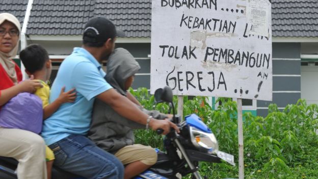 Penduduk di Bekasi melewati tulisan tolak pembangunan gereja di dekat GPIB Filadelfia, Bekasi, yang disegel pada 25 Desember 2012.