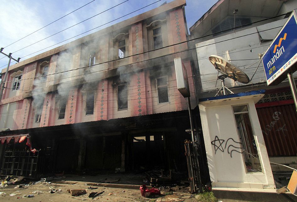 Asap masih mengepul dari sebuah bangunan yang terbakar di Jayapura, Papua, Jumat (30/8/2019). Sejumlah bangunan dan kendaraan terbakar saat aksi unjuk rasa yang berakhir rusuh di Jayapura, Kamis kemarin, masih terkait memprotes dugaan tindak rasisme kepada mahasiswa Papua di Jawa Timur beberapa wakt