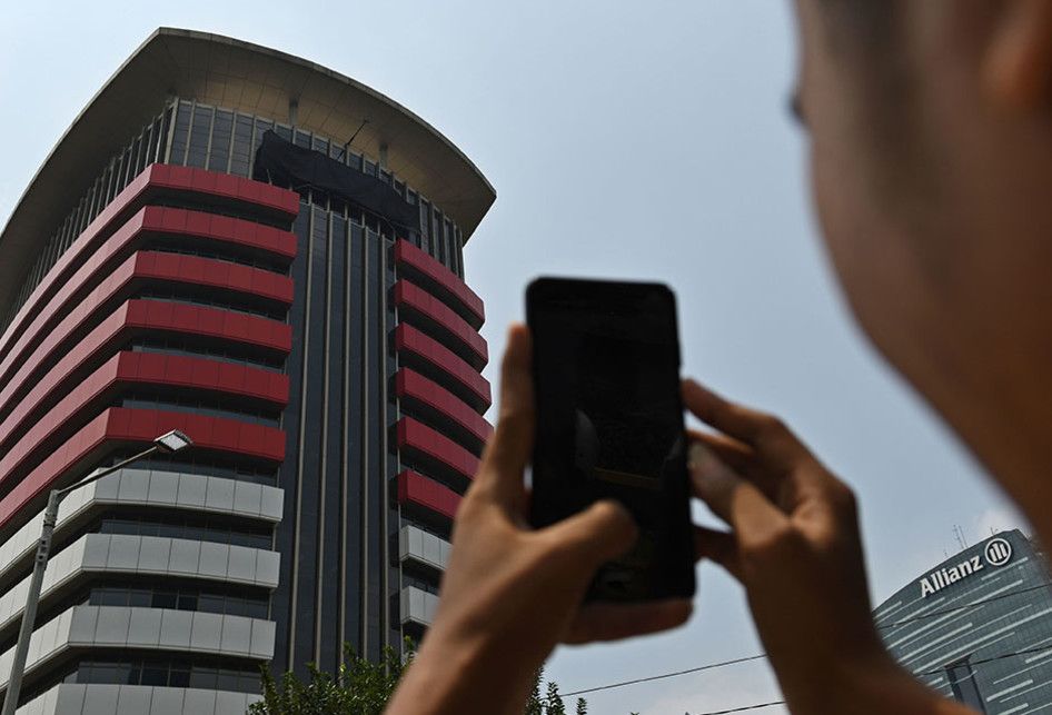 Warga memotret tulisan Komisi Pemberantasan Korupsi (KPK) yang tertutup kain hitam di Gedung Merah Putih KPK, Jakarta, Senin (9/9/2019). Penutupan tulisan KPK dengan kain hitam yang dilakukan sejak Minggu (8/9/2019) itu merupakan bagian dari aksi simbolis jajaran pimpinan hingga pegawai KPK jika rev