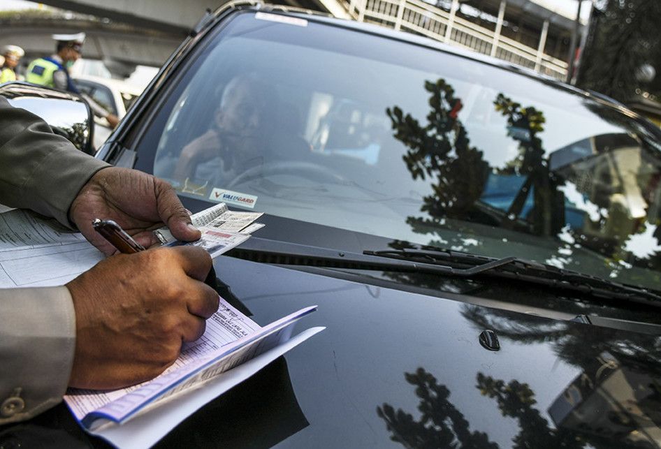 Petugas kepolisian menilang mobil berplat nomor genap yang memasuki Jalan Salemba Raya, di Matraman, Jakarta, Senin (9/9/2019). Petugas kepolisian mulai memberlakukan penindakan berupa tilang terhadap pengendara mobil yang melanggar di kawasan perluasan sistem ganjil-genap.