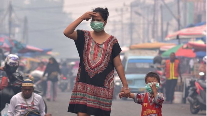 Seorang ibu dan anaknya mengenakan masker saat asap kebakaran hutan dan lahan (Karhutla) menyelimuti Kota Pekanbaru, Riau, Selasa (10/9). 