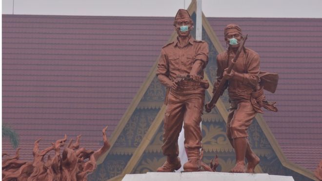 Dua patung di Monumen Perjuangan Rakyat Riau bermasker saat kabut asap pekat menyelimuti Kota Pekanbaru, Riau, Sabtu (14/9). Belum bisa dipastikan siapa yang memasang masker di patung itu.