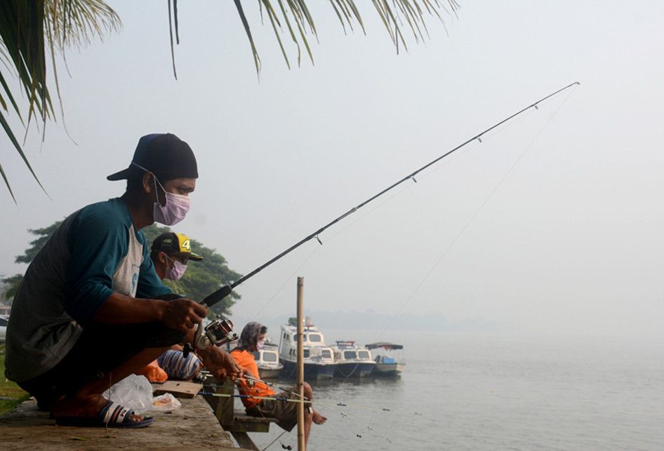 Sejumlah pemancing menggunakan saat memancing di tengah kabut di Tepian Kayan, Tanjung Selor, Kaltara, Minggu (15/09/2019). Kabut asap tak menyurutkan niat warga Kalimantan Utara beraktifitas di luar ruangan meski tetap menggunakan masker.