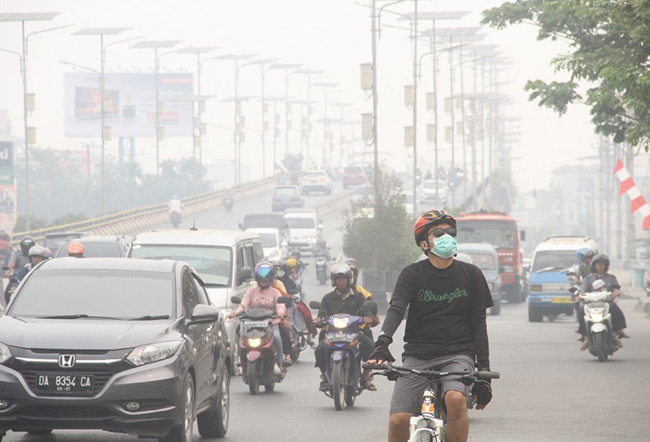 Warga bersepeda menggunakan masker pelindung pernapasan ketika melintas di Jalan Ahmad Yani yang terpapar kabut asap di Banjarmasin, Kalimantan Selatan, Minggu (15/9/2019). Kebakaran hutan dan lahan (Karhutla) di sejumlah wilayah Provinsi Kalsel mengakibatkan Kota Banjarmasin terpapar kabut asap den