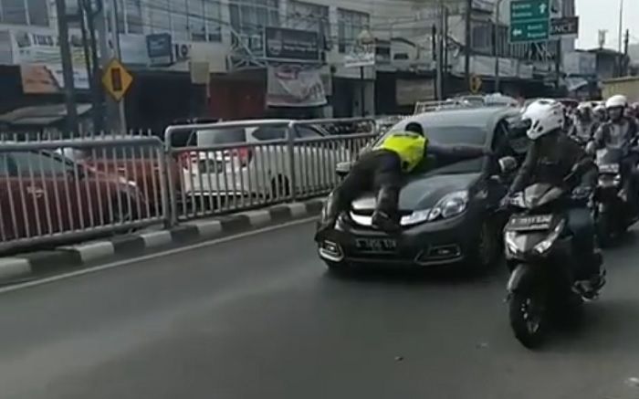 Polisi gelantungan di kap mobil, untuk hentikan pelanggar lalu lintas di kawasan Pasar Minggu, Jaksel (16/9/2019).