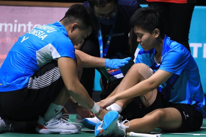 Pebulu tangkis ganda putri Indonesia, Apriyani Rahayu membantu melepas sepatu Siti Fadia Silva Ramadhanti setelah mengalami cedera  pada semifinal Malaysia Open 2023 di Axiata Arena, Kuala Lumpur, Sabtu (14/1/2023).