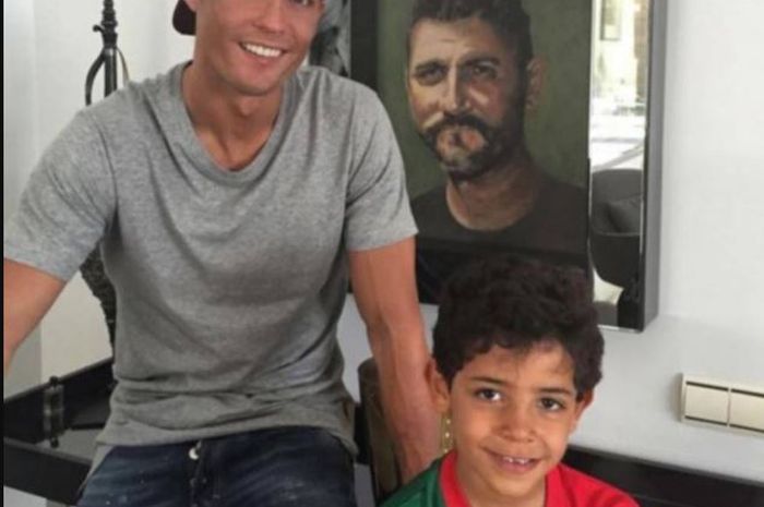 Cristiano Ronaldo dan sang putra, Cristiano Jr. Berdiri di depan foto ayah Ronaldo Jose Dinis Aveiro