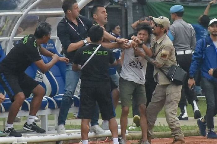 Pelatih Persib Bandung Miljan Radovic (kedua dari kiri) coba melindungi diri saat didatangi seorang suporter yang diduga hendak memukulnya di Stadion Si Jalak Harupat, Kabupaten Bandung, Kamis (7/3/2019) sore WIB, dalam duel Persib versus Persebaya Surabaya di Piala Presiden 2019.