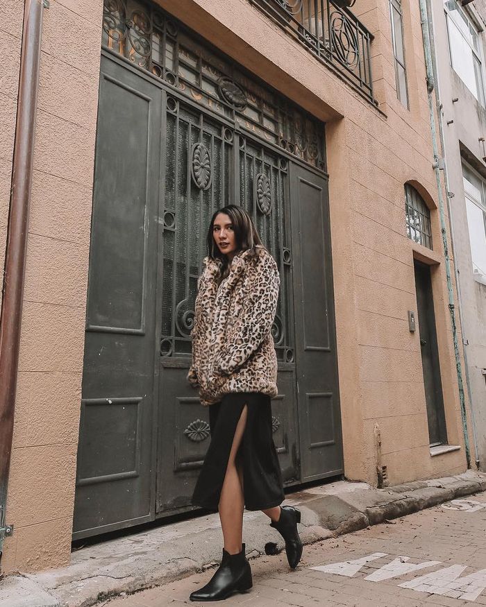 Acha Sinaga terlihat tampil stylish dnegan slit dress yang dipadukan dengan jaket bulu motif leopard