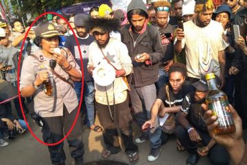 Kompol Sarce Christiaty Leo Dima saat membagikan minuman keras pada mahasiswa Papua yang sedang berunjuk rasa.