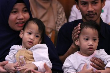 Bayi kembar siam asal Kendari, Sulawesi Tenggara Azila (kiri) digendong ibunya Silvina Dewi dan Aqila (kanan) digendong bapaknya Jayasri, di Rumah Sakit Umum Daerah (RSUD) Dr Soetomo, Surabaya, Jawa Timur, Jumat (15/11)