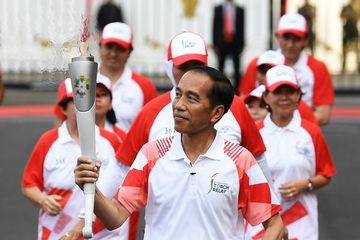 Presiden Joko Widodo (tengah) membawa obor Asian Games XVIII saat prosesi kirab di halaman Istana Merdeka, Jakarta, Jumat (17/8). 