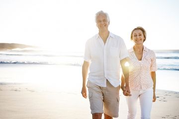 Pasangan tua yang bahagia berjalan di pantai