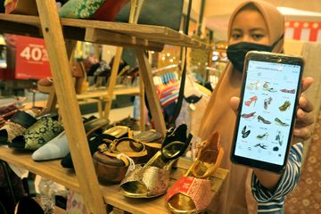 Pelaku usaha menunjukkan katalog online produk sepatu berbahan tenun songket milik merk Nadina Salim mitra Binaan PT Pupuk Sriwidjaja (Pusri) dipajang di salah satu gerai UMKM di Palembang,Sumsel, Senin (20/7/2020). PT Pusri mendorong Mitra UKM binaan untuk dapat meningkatkan promosi melalui platfor