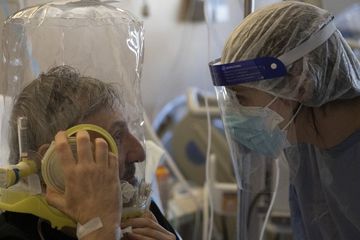 Seorang pasien yang bernapas di bawah ventilasi tutup kepala CPAP (Continuous Positive Air Pressure) oksigen berbicara dengan dokter di unit Covid-19 sub-intensif Rumah Sakit Poliklinik Tor Vergata, di Roma.