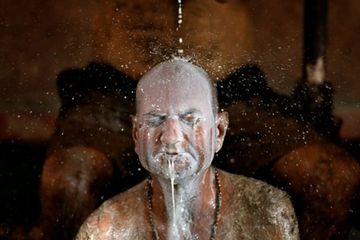 Seorang pria di India mandi dengan susu sapi untuk menghilangkan kotoran sapi dari tubuhnya selama &quot;terapi kotoran sapi&quot;. 