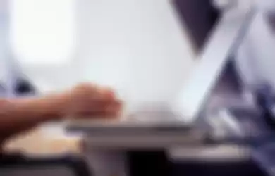 Woman typing on laptop computer in commercial airplane