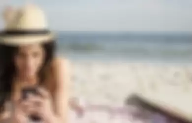 USA, New York State, Rockaway Beach, Woman using cell phone on beach