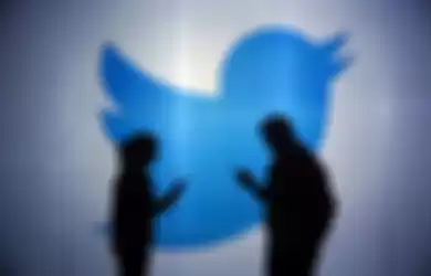 People are seen as silhouettes as they check mobile devices whilst standing against an illuminated wall bearing Twitter Inc.'s logo in this arranged photograph in London, U.K., on Tuesday, Jan. 5, 2016. Twitter Inc. may be preparing to raise its character limit for tweets to the thousands from the current 140, a person with knowledge of the matter said. Photographer: Chris Ratcliffe/Bloomberg via Getty Images