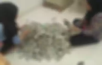 Dua karyawan yang sedang menghitung uang pecahan Rp 2.000 dari ibu Muspina