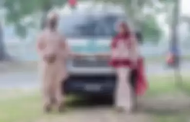 Pasangan pengantin yang mengambil foto pernikahan berlatar belakang mobil jenazah, 
