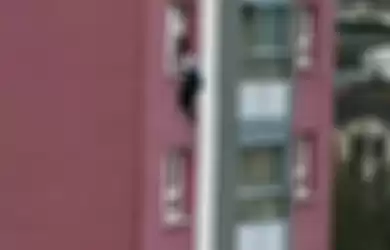 seorang saksi mengambil foto saat Alem masih berusaha meraih ambang jendela apartemen.