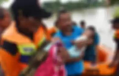 Relawan Badan Penanggulangan Bencana Daerah (BPBD) mengevakuasi dua balita saat terjadi banjir di Desa Kedungrejo, Pilangkenceng, Kabupaten Madiun,  Jawa Timur, Rabu (6/3/2019). Sejumlah anak Sungai Madiun meluap dan merendam sejumlah desa di wilayah tersebut, sehingga ratusan warga yang terjebak ba