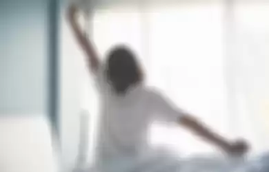 Asian woman waking up in the morning. Outstretched arms.
