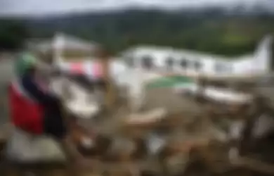 Warga mengamati sebuah pesawat yang terseret banjir bandang di Sentani, Jaya Pura, Papua, Senin (18/3/2019). Akibat banjir bandang yang melanda Sentani sejak Sabtu (16/3) lalu, sedikitnya empat ribu warga mengungsi di sejumlah posko pengungsian. 