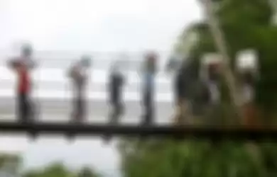  Petugas melintasi Jembatan Gantung.