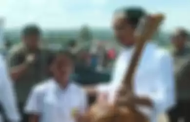 Seorang siswi SMP memberikan sebuah gitar kayu kepada Jokowi sambil berlinangan air mata, saat sang presiden bberkunjung ke Danau Toba