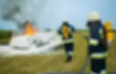 Ilustrasi Mobil terbakar dipadamkan oleh pemadam kebakaran.