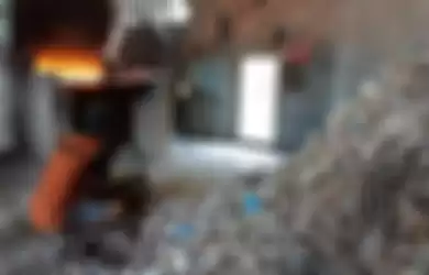 Pekerja mengambil sampah plastik impor untuk bahan bakar tungku pemasak kedelai pada industri tahu di Desa Tropodo, Sidoarjo, Selasa (18/6/2019). 