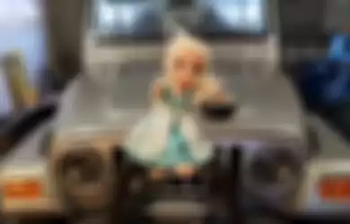 Boneka Elsa yang diikatkan pada kap mobil Chris