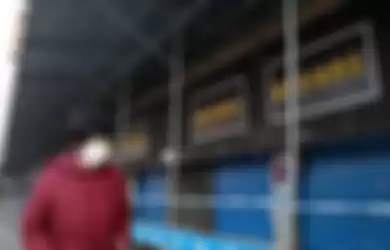 Seorang perempuan melintas di depan pasar ikan di Kota Wuhan, China, yang ditutup terkait dugaan sebagai lokasi awal merebaknya virus misterius di negara itu, Minggu (12/1/2020). Virus misterius mirip pneumonia telah menjangkiti puluhan orang dan menelan korban jiwa kedua di China, menurut pemerintah setempat