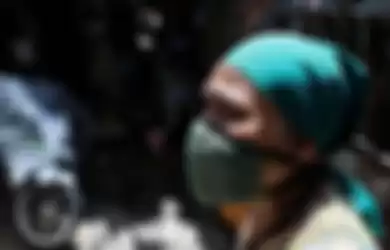 Seorang warga menggunakan masker berdiri didepan rumahnya di Jalan Tambora RT 01/07, Kelurahan Tambora, Jakarta Barat, Rabu (1/4/2020). Sejumlah kelurahan di Ibu Kota mulai menutup akses jalan untuk mencegah penyebaran virus corona atau COVID-19.