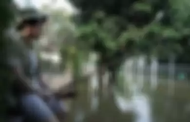 Nicholas Sean yang memancing di depan rumahnya yang terendam banjir air rob.