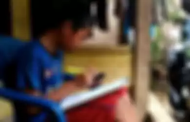 Jonathan (13) pelajar SMP di Bandar Lampung sedang memahami soal dari pembelajaran daring kelasnya, Kamis (6/8/2020). Untuk memenuhi kebutuhan kuota internet, Jonathan berjualan pempek di sekitar kampung.