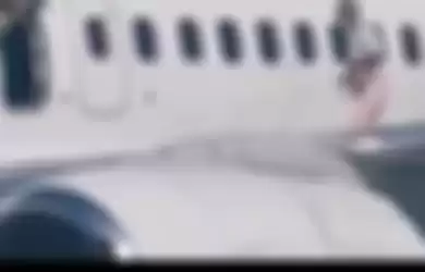 Wanita ini berjalan di atas sayap pesawat seusai membuka pintu daruat karena kegerahan di Bandara Borysphil, Kiev, Ukraina, Senin (31/8/2020) waktu setempat. 