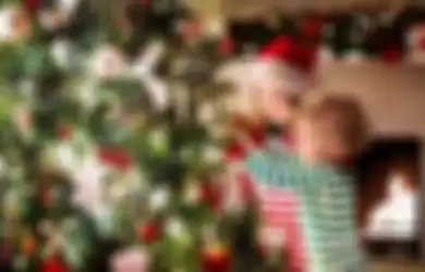 Ilustrasi anak memasang candy cane di pohon natal.