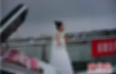 Jing yang mengenakan gaun pengantin berdiri di samping mahar sebuah mobil mewah dan sekoper uang tunai senilai Rp 400 juta.